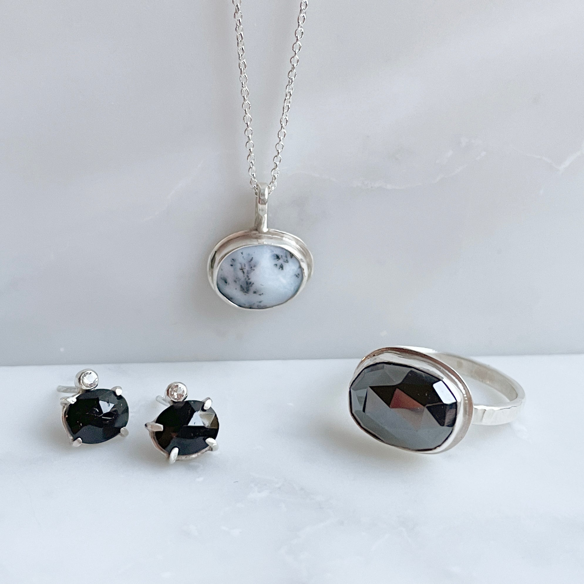 Silver jewelry set with black gemstones on a white surface