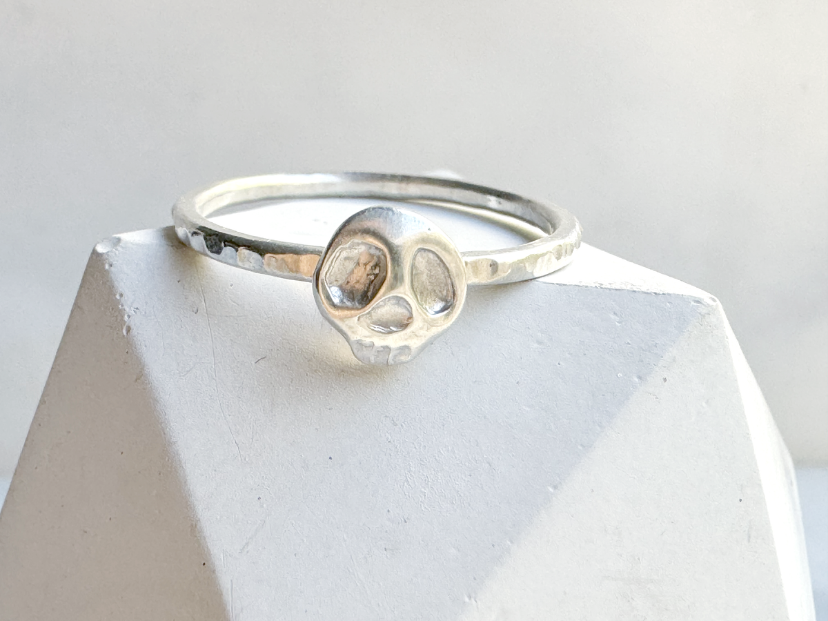 Silver ring with a skull design on a white stone surface