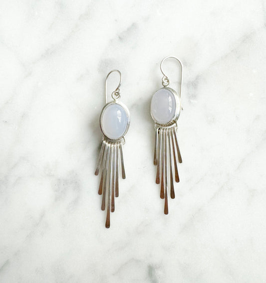 Pair of earrings with light purple stones and fringe on a marble background