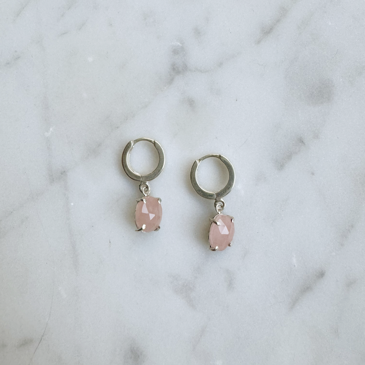 guava quartz huggie hoops in silver on marble background